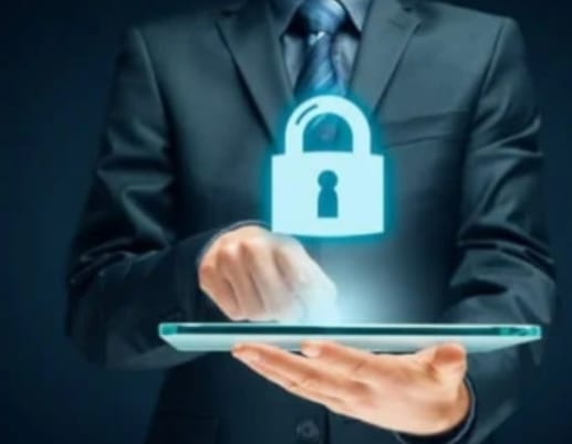 "A businessman in a suit holding a tablet with a glowing blue padlock icon above it, symbolizing digital security or data protection."
