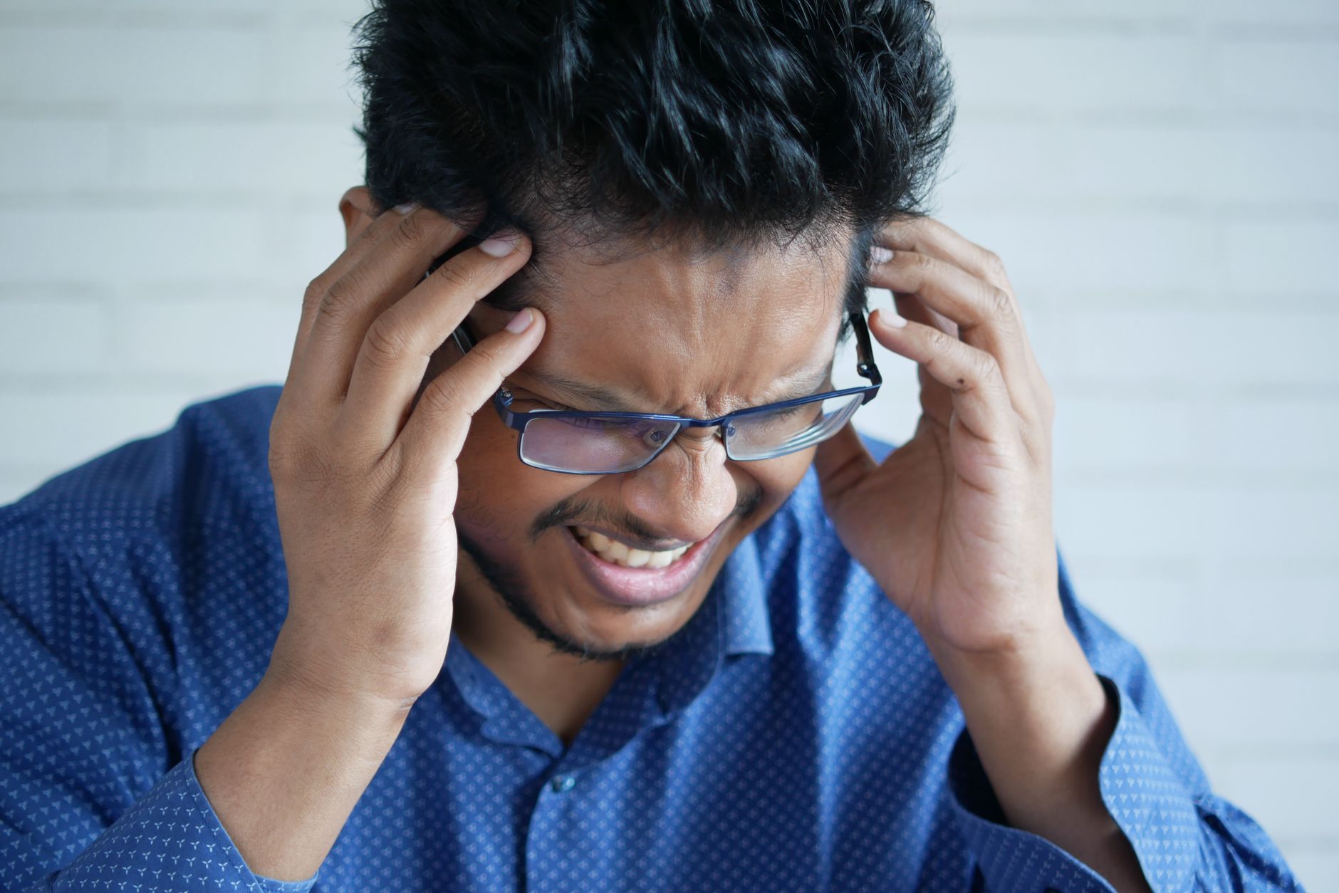 man in blue long sleeves having a headache