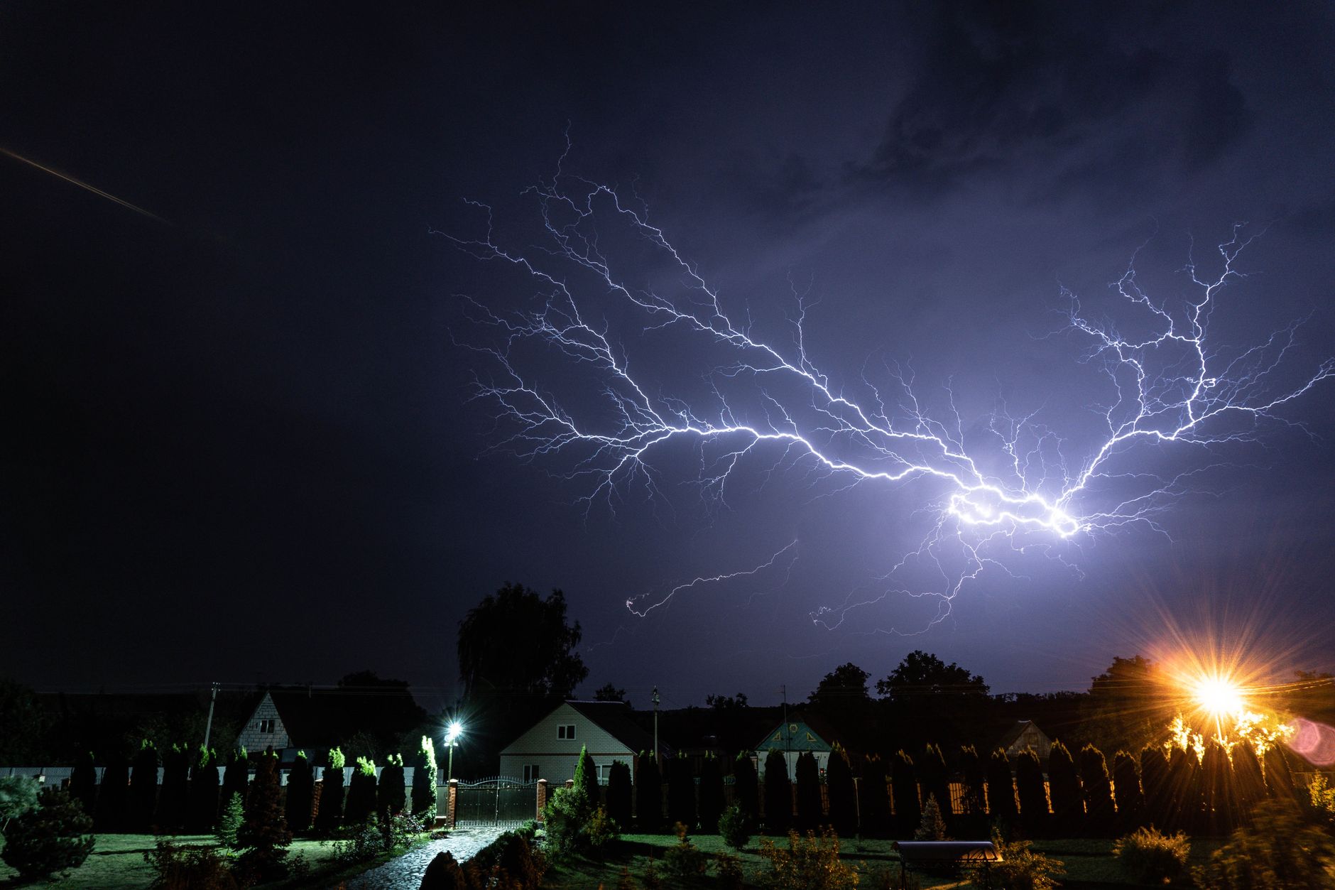 photo of a thunderstorm above houses at night